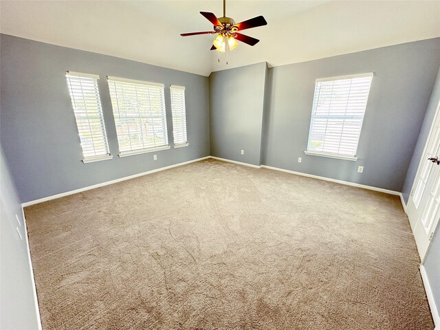carpeted empty room with a ceiling fan, lofted ceiling, and baseboards