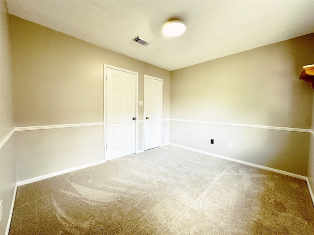 carpeted spare room featuring visible vents and baseboards