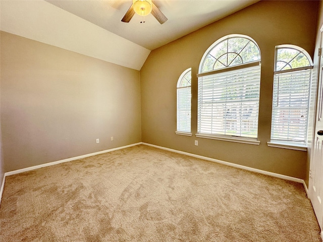 carpeted spare room with lofted ceiling, a ceiling fan, and baseboards