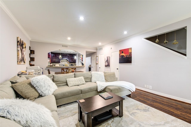 living area with wood finished floors, ornamental molding, visible vents, and recessed lighting