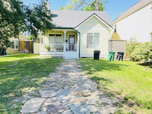 view of front of house featuring a front yard, fence, and covered porch