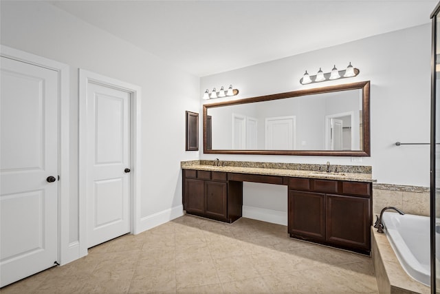 full bathroom featuring a bath, baseboards, a sink, double vanity, and tile patterned flooring