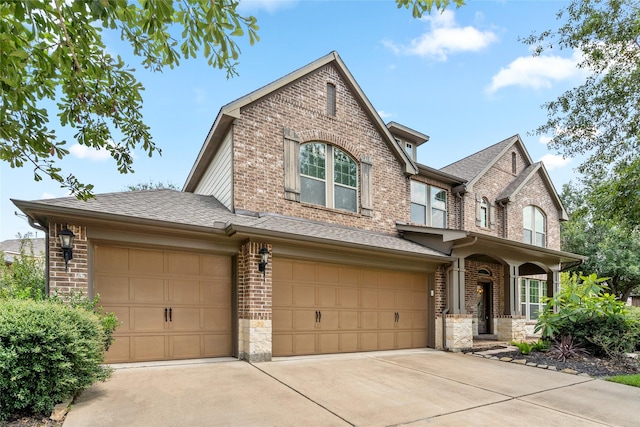 craftsman inspired home featuring roof with shingles, brick siding, and driveway