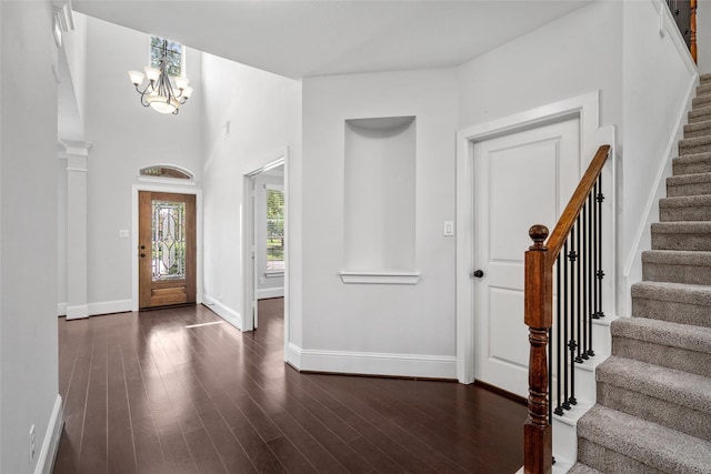foyer with baseboards, dark wood-style floors, an inviting chandelier, and stairs
