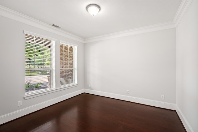 spare room featuring dark wood-type flooring, visible vents, baseboards, and ornamental molding