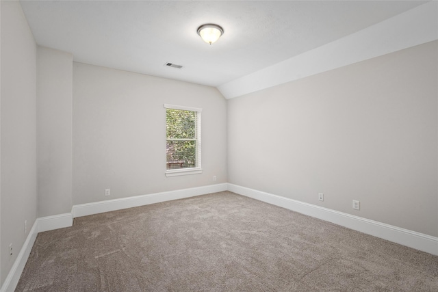 unfurnished room featuring carpet, visible vents, baseboards, and lofted ceiling