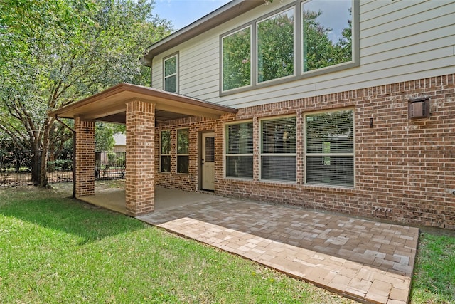rear view of property with brick siding, fence, a patio, and a lawn