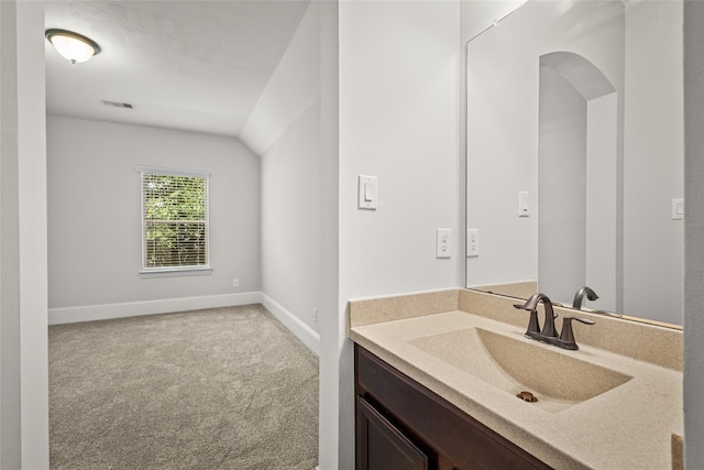 bathroom with visible vents, baseboards, vanity, and lofted ceiling