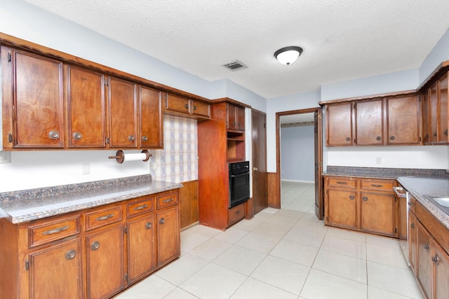 800 Fairway Dr, Richmond, TX 77469 - kitchen featuring brown cabinets, visible vents, a textured ceiling, and black oven