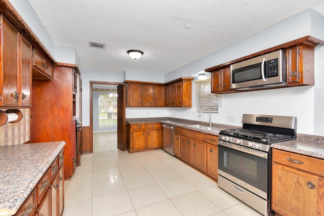 800 Fairway Dr, Richmond, TX 77469 - kitchen with visible vents, a sink, appliances with stainless steel finishes, a textured ceiling, and brown cabinetry