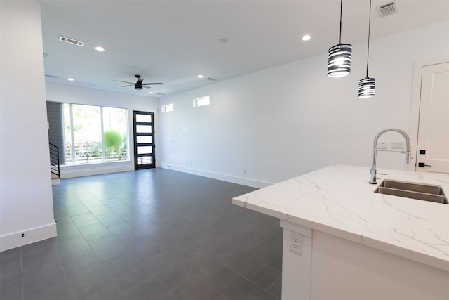interior space featuring visible vents, baseboards, a ceiling fan, and a sink