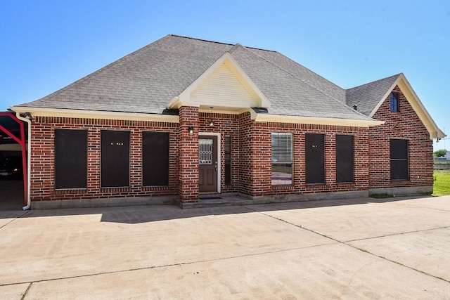 exterior space featuring brick siding and roof with shingles