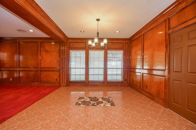 empty room with a chandelier, a decorative wall, and crown molding
