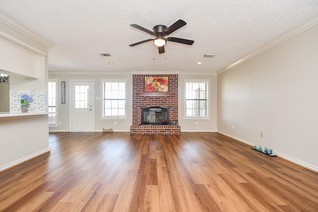 unfurnished living room with ceiling fan, ornamental molding, visible vents, wood finished floors, and a healthy amount of sunlight