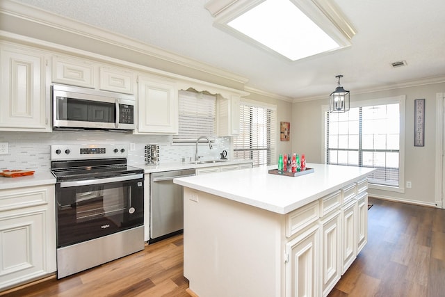 kitchen featuring a sink, light countertops, light wood-type flooring, appliances with stainless steel finishes, and decorative backsplash