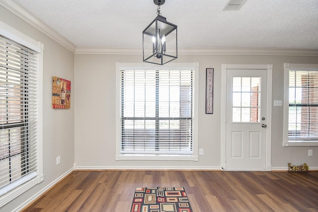unfurnished dining area with visible vents, a notable chandelier, ornamental molding, a textured ceiling, and wood finished floors