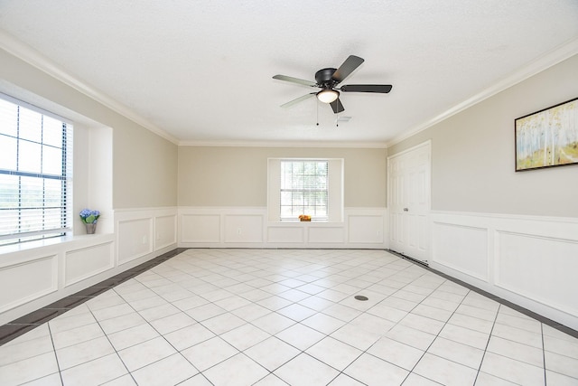 spare room with crown molding, a wainscoted wall, a ceiling fan, and a decorative wall