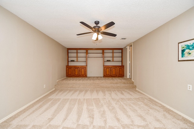 unfurnished living room featuring visible vents, light colored carpet, a ceiling fan, and a textured ceiling