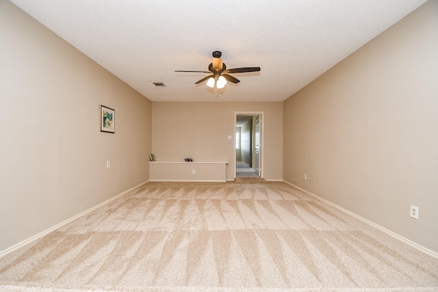 empty room with ceiling fan, light carpet, and baseboards
