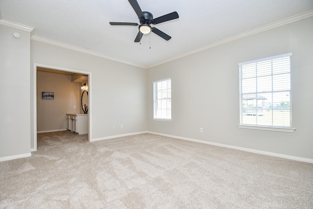 spare room with light carpet, baseboards, ornamental molding, and ceiling fan