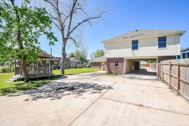 view of home's exterior featuring a carport, a lawn, fence, brick siding, and driveway