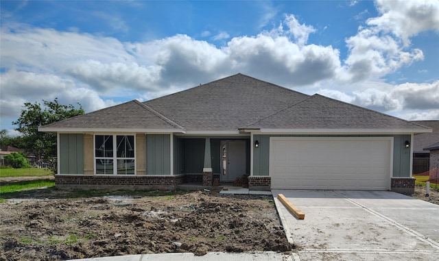 ranch-style home featuring board and batten siding, an attached garage, a shingled roof, and brick siding