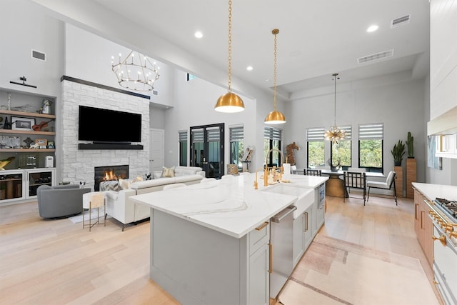 513 Pineal Dr, Montgomery, TX 77316 - kitchen with stainless steel dishwasher, a sink, a towering ceiling, a chandelier, and light wood-style floors