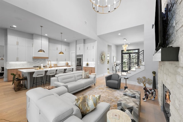513 Pineal Dr, Montgomery, TX 77316 - living room with a chandelier, a towering ceiling, light wood-style floors, a fireplace, and baseboards