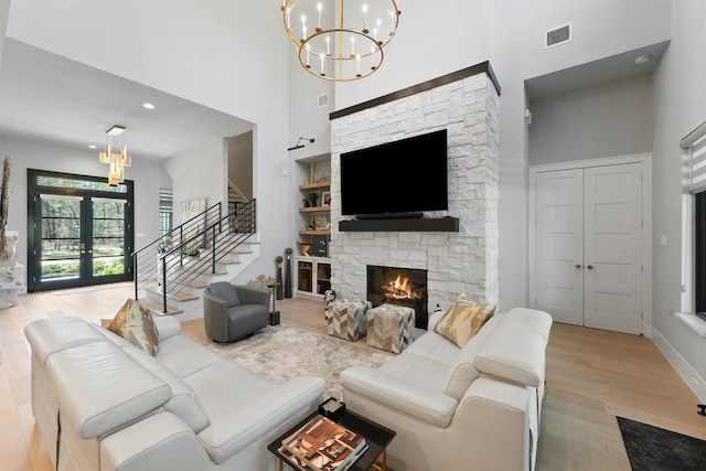 513 Pineal Dr, Montgomery, TX 77316 - living room with a chandelier, a high ceiling, a stone fireplace, wood finished floors, and stairs