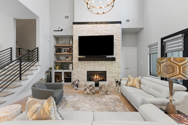 513 Pineal Dr, Montgomery, TX 77316 - living area featuring a high ceiling, a chandelier, a stone fireplace, wood finished floors, and stairs