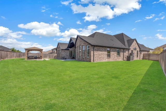 back of property featuring a lawn, a fenced backyard, a gazebo, and brick siding
