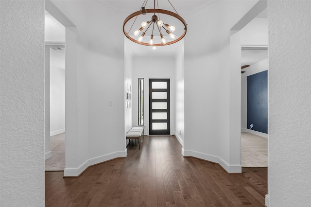 foyer with a textured wall, baseboards, wood finished floors, and a chandelier