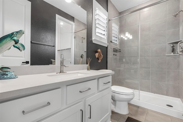 bathroom with a shower stall, toilet, tile patterned flooring, and vanity