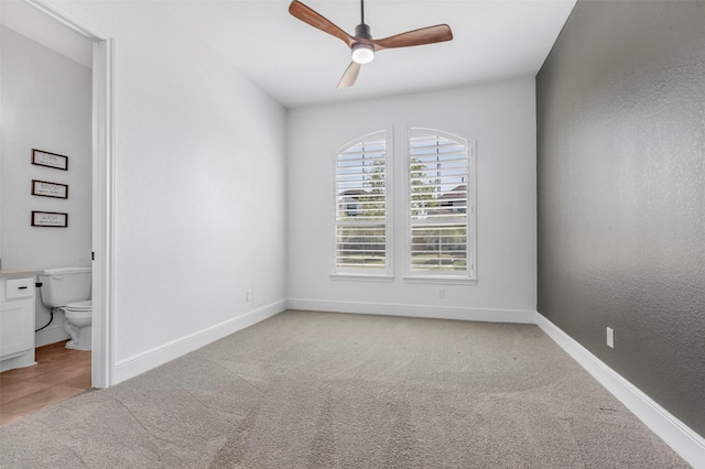 unfurnished room featuring a ceiling fan, baseboards, and light carpet