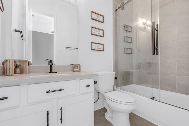 full bath featuring toilet, vanity, tile patterned floors, and combined bath / shower with glass door