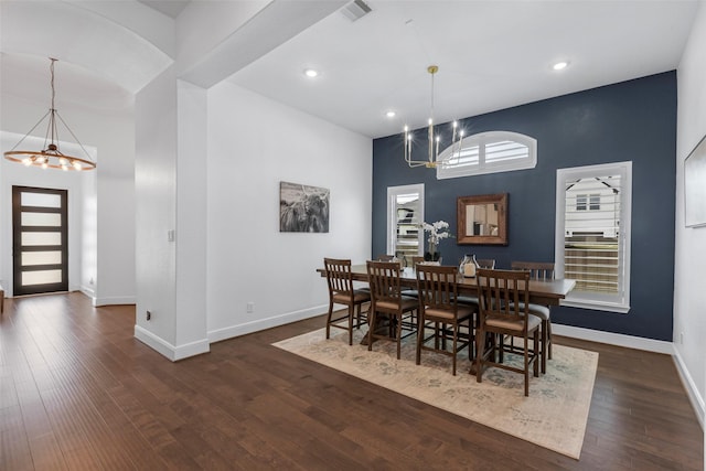 dining room with visible vents, baseboards, a notable chandelier, wood finished floors, and a high ceiling