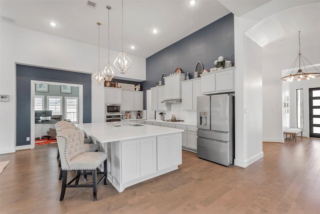 kitchen with light countertops, a notable chandelier, a towering ceiling, and stainless steel appliances