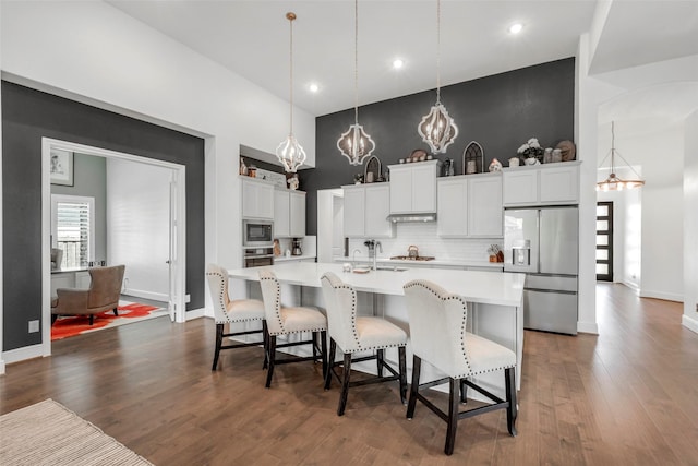 kitchen featuring stainless steel appliances, a kitchen breakfast bar, dark wood finished floors, a chandelier, and light countertops