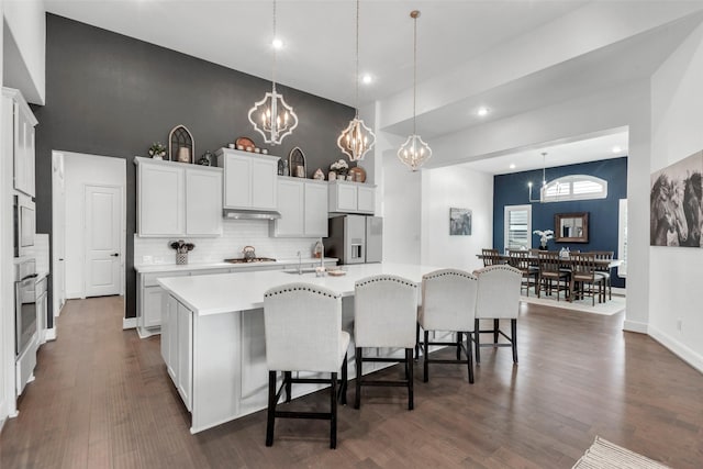kitchen featuring a large island, a towering ceiling, appliances with stainless steel finishes, light countertops, and a notable chandelier