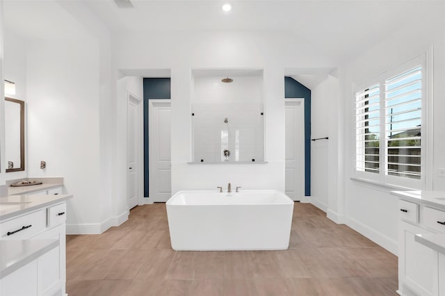 bathroom with a freestanding bath, baseboards, vanity, and tiled shower