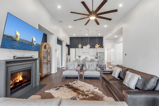 living room featuring dark wood-style floors, visible vents, a glass covered fireplace, recessed lighting, and ceiling fan