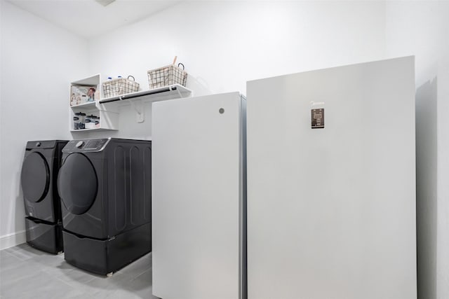 clothes washing area with baseboards, independent washer and dryer, laundry area, and light tile patterned floors
