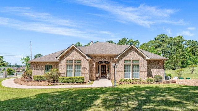 12434 Longmire Way, Conroe, TX 77304 - view of front of house with brick siding, a front yard, roof with shingles, and a chimney