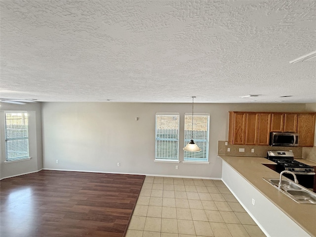 12223 Forstall Dr, Houston, TX 77014 - kitchen with a sink, brown cabinetry, stainless steel appliances, light countertops, and baseboards
