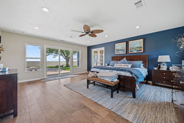 bedroom with wood finished floors, visible vents, baseboards, and access to outside