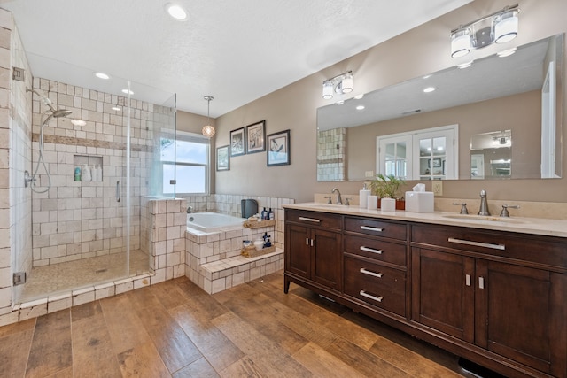 full bath with a garden tub, wood finished floors, a sink, and a shower stall