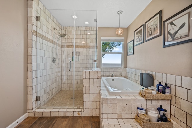 full bathroom featuring wood finished floors, a jetted tub, and a shower stall