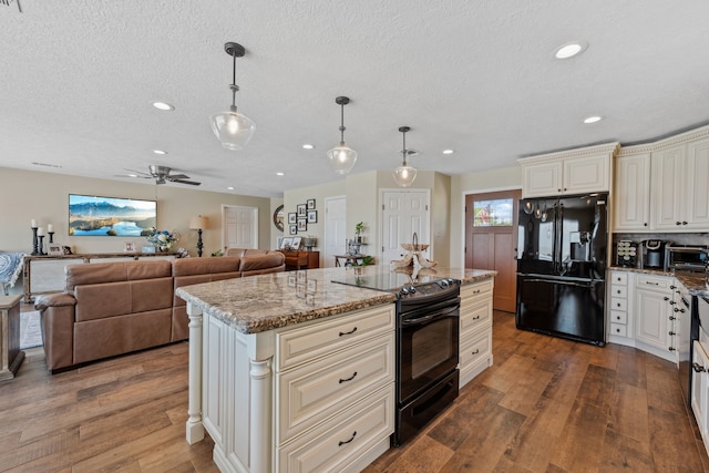 kitchen featuring wood finished floors, light stone counters, a textured ceiling, and black appliances