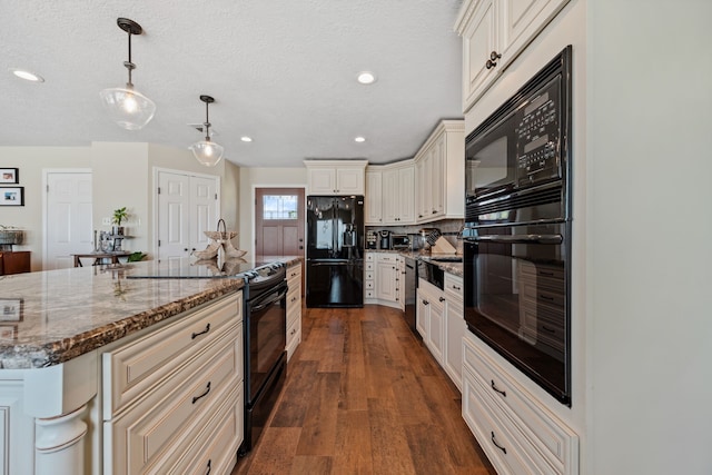 kitchen featuring a center island, dark stone counters, dark wood-style flooring, pendant lighting, and black appliances