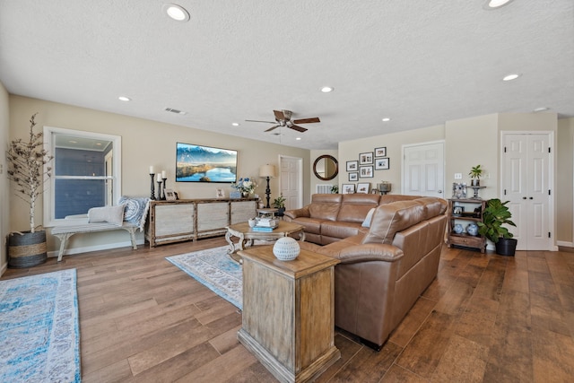living room with wood finished floors, a textured ceiling, and recessed lighting